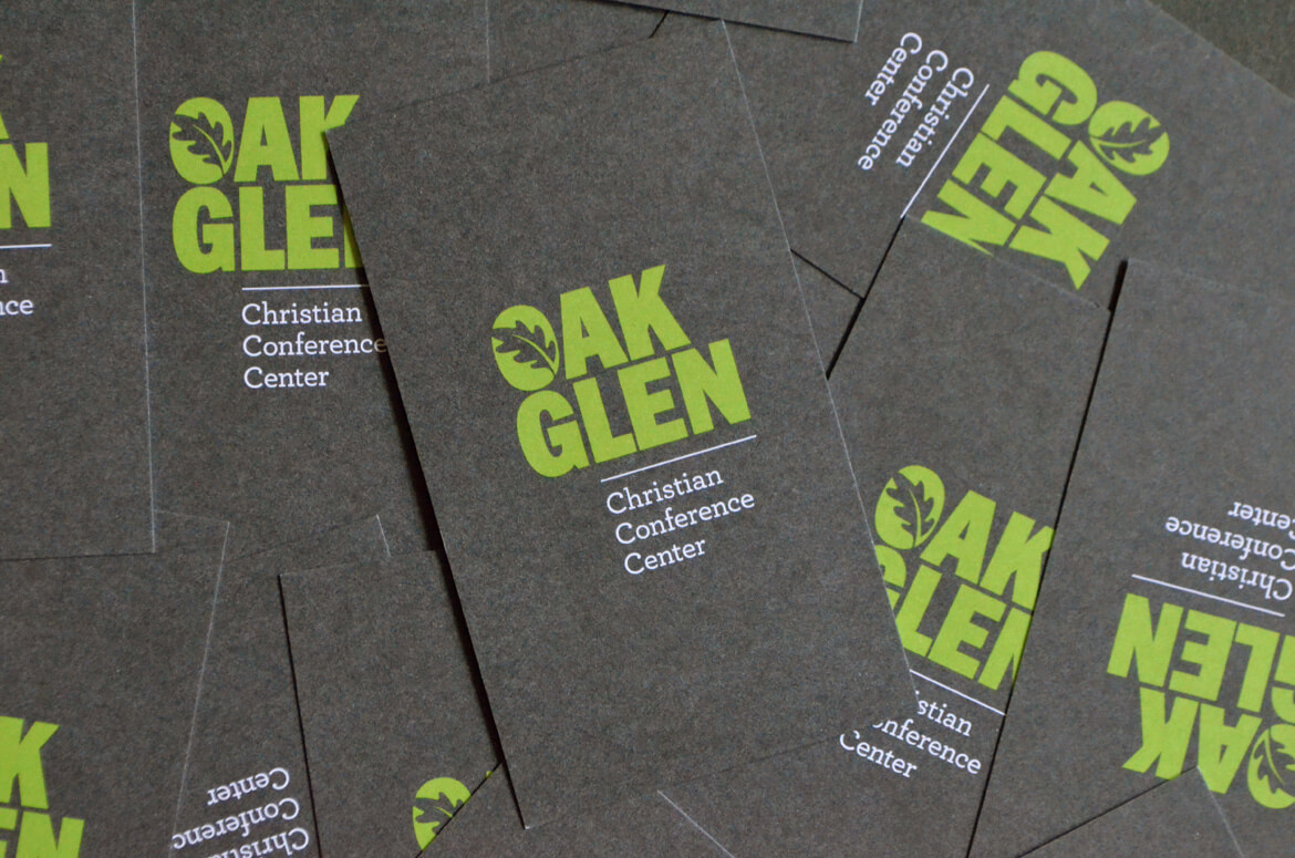 A stack of dark gray business cards printed on textured uncoated paper.