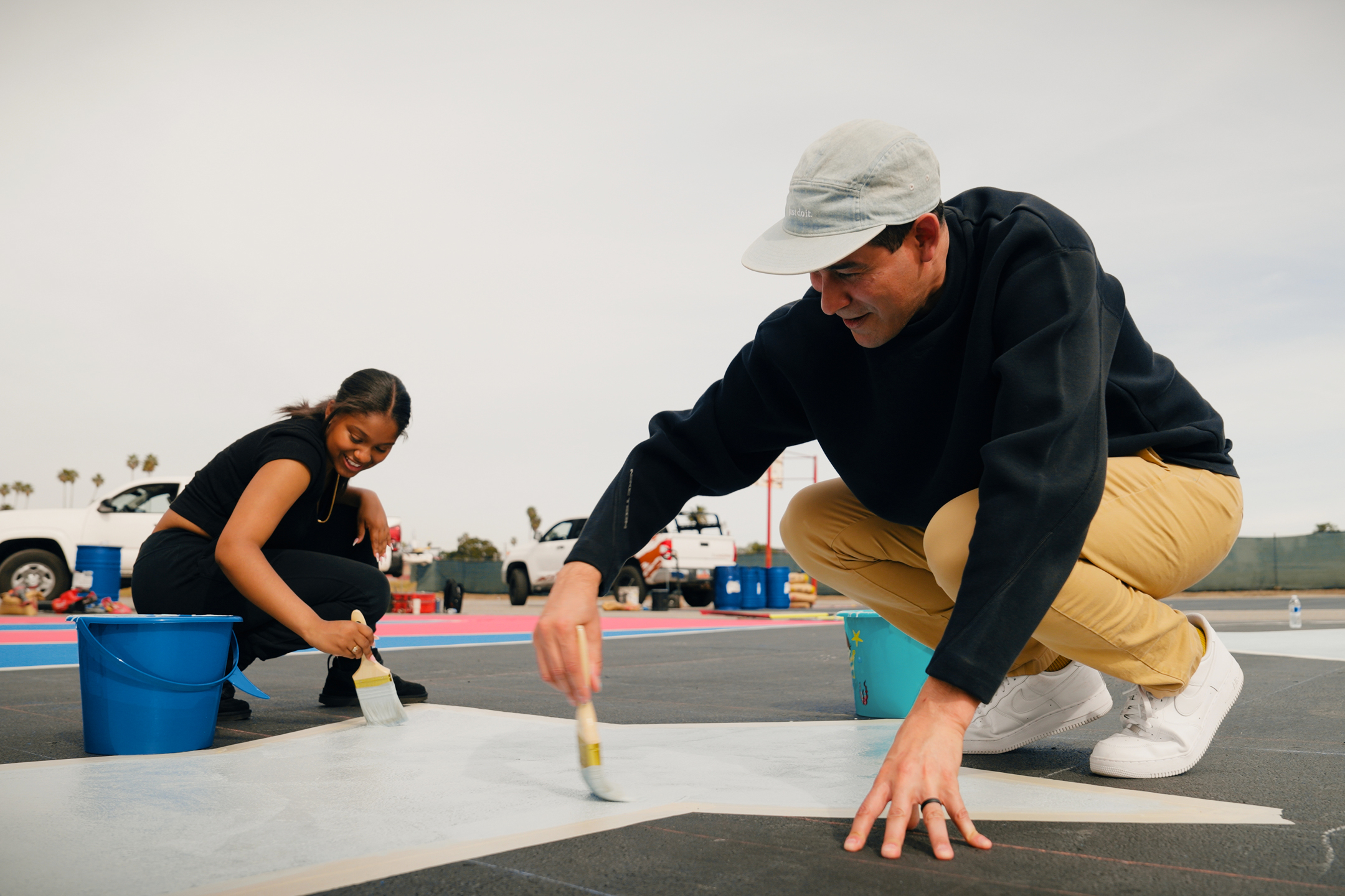 Ben and student painting a court at Inglewood High School